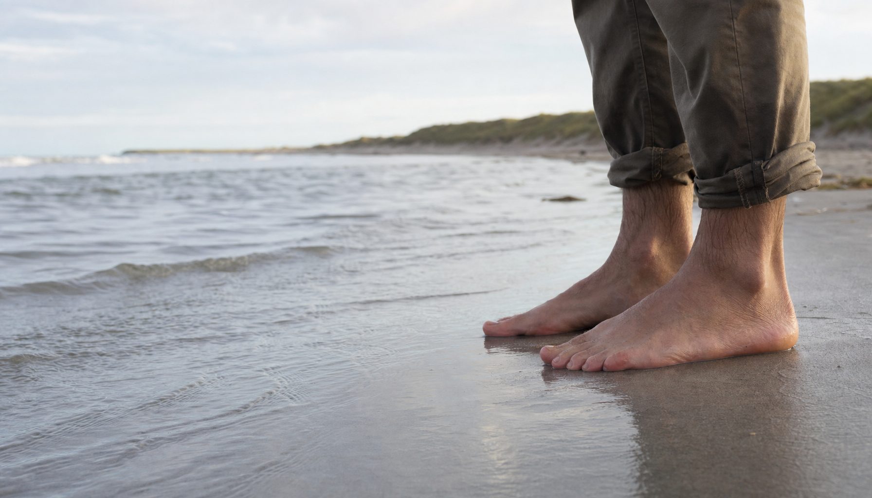 Bare fødder på vådt sand ved den danske kyst